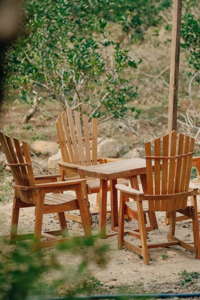 Wooden chairs and table set in a tranquil outdoor garden scene, ideal for relaxation.